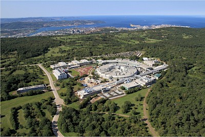 Foto 2 - vista aerea del Sincrotrone Elettra e laboratorio CNR-IOM con Trieste in sfondo, Credits: Elettra Sincrotrone Trieste, il fotografo è Gabriele Crozzoli.